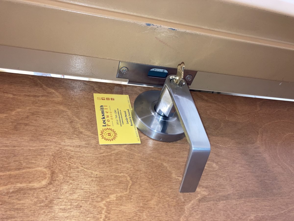 Commercial lever door lock installation by Locksmith Powell Ohio with business card showing locally owned bonded and insured service