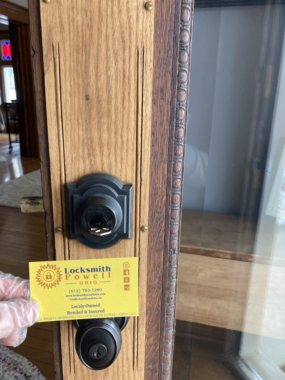 Locksmith Powell Ohio servicing a Baldwin residential door lock on a wood front door in Powell Ohio — locally owned bonded and insured